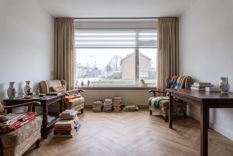 Dezelfde woonkamer met nieuwe gordijnen, een rolgordijn en een visgraatvloer